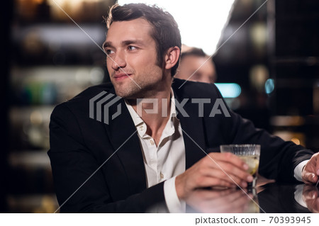 a handsome man in a shirt and jacket with a cocktail in his hands in a bar, portrait, close-up 70393945