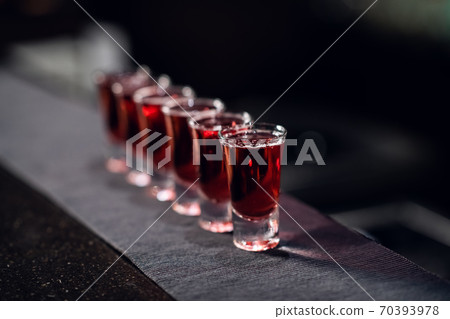 a row of shots with red liquor on the bar on the fabric close up a row of shots with red liquor on the bar on the fabric close up 70393978