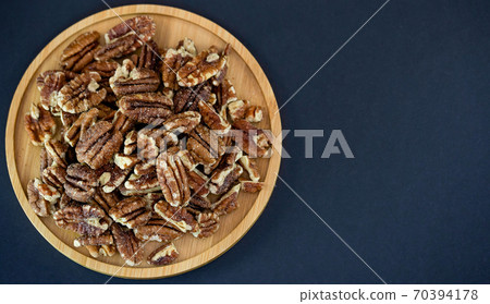 pecan nut or Pekannuss nuts group Protein and healthy food for diet in a wooden plate on a black background. 70394178