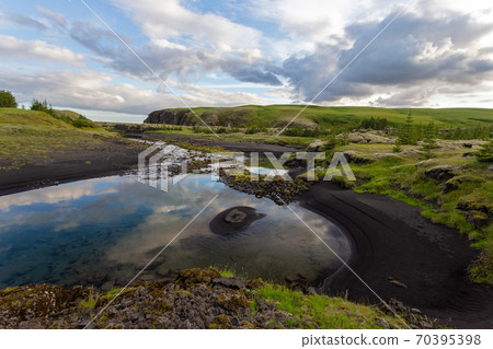 Summer nature scenery with black sand on a riverbank and clouds in the sky. Summer nature scenery with black sand on a riverbank and clouds in the sky. 70395398