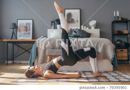 Fitness woman working out at home and doing single-leg glute bridge 70395901