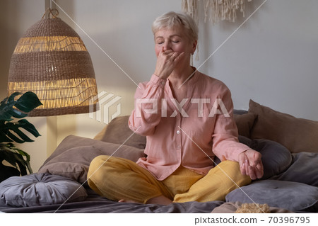 Senior woman practicing yoga at home, making Alternate Nostril Breathing exercise, nadi shodhana pranayama 70396795