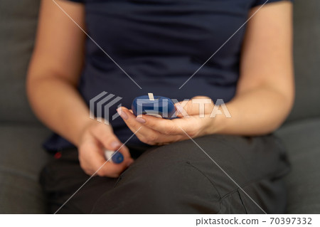 Close up of middle aged woman hands with glucose meter. Blood testing at home. Metabolic syndrome 70397332