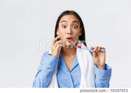 Daily routine, morning and hygiene concept. Excited and intrigued asian girl in blue pajama with towel and toothbrush hear about new toothpaste, wanting try and use promo discount 70397953
