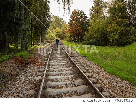 the girl walks along the railway track and there are green trees around the girl walks along the railway track and there are green trees around 70398039