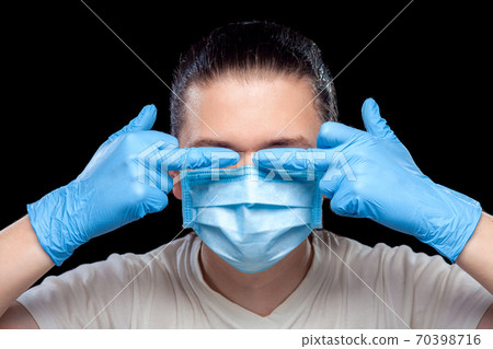 hands in gloves show obscene gesture with middle fingers covering eyes on corruption male portrait of a doctor in a medical mask, closeup isolated on black background. 70398716