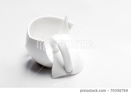fragments of parts a broken cup with a handle after falling on a white surface with a copy space, concept on the theme of the collapse of the crisis. fragments of parts a broken cup with a handle after falling on a white surface with a copy space, concept on the theme of the collapse of the crisis. 70398769