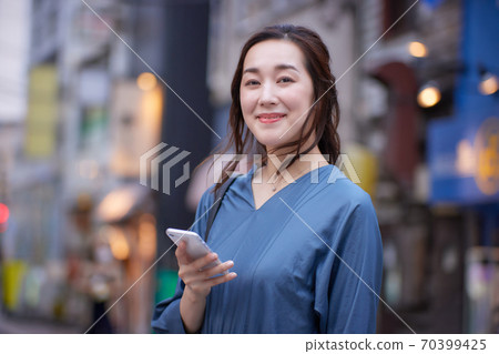 一個女人在黃昏時在街角上拿著智能手機 70399425