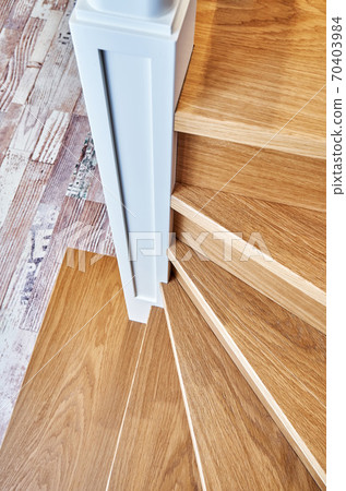 Winder steps of a wooden staircase with white balusters. View from above 70403984