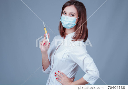 Young doctor in medical mask with a syringe Young doctor in medical mask with a syringe 70404188