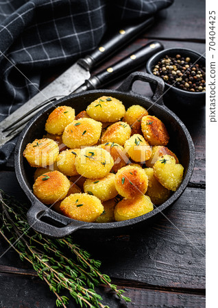 Homemade Potato Gnocchi fried in a pan. Black wooden background. Top view. Homemade Potato Gnocchi fried in a pan. Black wooden background. Top view. 70404425