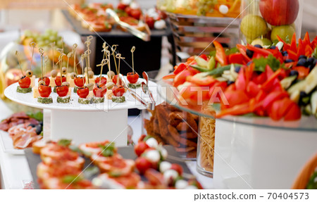 Catering. The table is richly richly filled with various snacks and vegetables. Focus on tomato and cheese snacks 70404573
