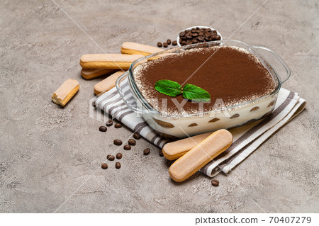 Traditional Italian Tiramisu dessert in glass baking dish and savoiardi cookies on concrete background Traditional Italian Tiramisu dessert in glass baking dish and savoiardi cookies on concrete background 70407279