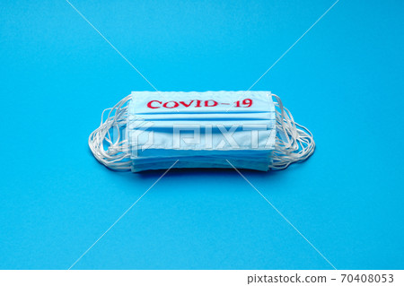 Stack of Disposable blue medical face masks with COVID-19 sign on blue background 70408053