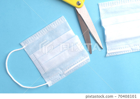 Cut medical protective mask and yellow scissors on a blue paper background. The concept of disposable protection against coronavirus Cut medical protective mask and yellow scissors on a blue paper background. The concept of disposable protection against coronavirus 70408101
