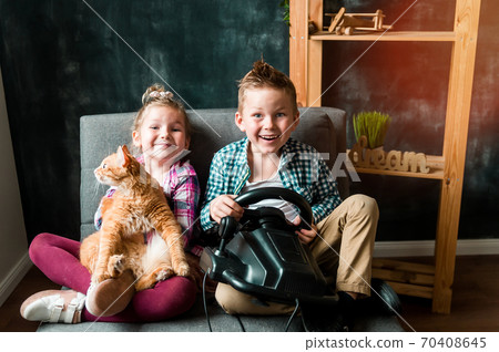 Happy children with pet in hands playing together. Girl and boy playing video game. Addiction. Happy children with pet in hands playing together. Girl and boy playing video game. Addiction. 70408645