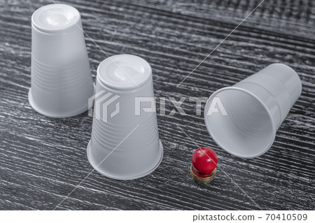 The winning open Cup in the shell game with a prize red ball of Euro coins. Standing next to 2 empty losing the Cup. The concept of a big money win in the game 70410509