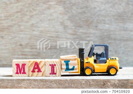 Toy forklift hold letter block l to complete word mail on wood background Toy forklift hold letter block l to complete word mail on wood background 70410920