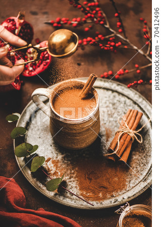 Human hand pouring cinnamon powder to turkish hot Human hand pouring cinnamon powder to turkish hot 70412496
