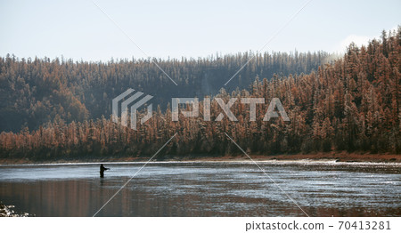 Profile of a fisherman on the background of the taiga river in autumn. Profile of a fisherman on the background of the taiga river in autumn. 70413281