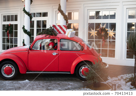 Smiling cute winter girl in red hat sitting in car 70413413