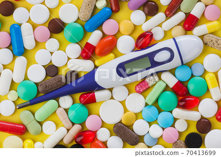 Pills and electronic thermometer with blank screen - medical background 70413699