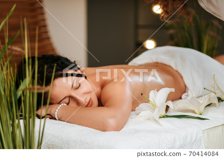Beautiful young woman in the massage salon with brown curly hair and healthy skin. Masseur and patient concept. Beautiful young woman in the massage salon with brown curly hair and healthy skin. Masseur and patient concept. 70414084