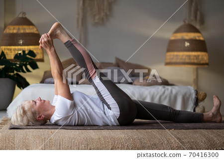 woman working out, warming up using yogic belt, lying in yoga Supta Padangushthasana, One Leg Lift exercise woman working out, warming up using yogic belt, lying in yoga Supta Padangushthasana, One Leg Lift exercise 70416300