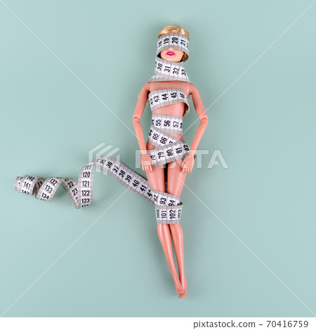 Doll wrapped in measuring tape. Tied up unrecognizable plastic doll, weight loss, fasting and slimming, diet, anorexia, overeating control, female fight for perfect fit body concept. Free copyspace Doll wrapped in measuring tape. Tied up unrecognizable plastic doll, weight loss, fasting and slimming, diet, anorexia, overeating control, female fight for perfect fit body concept. Free copyspace 70416759