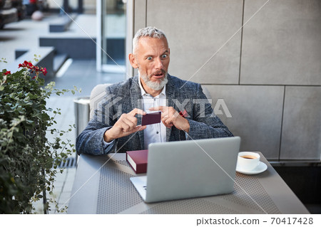 Thrilled senior citizen with a plastic card making a video-call Thrilled senior citizen with a plastic card making a video-call 70417428