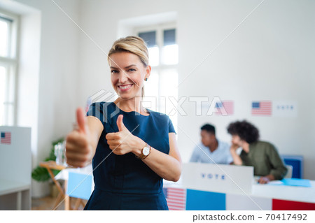 Portrait of happy woman voter with tumb up in polling place, usa elections concept. 70417492