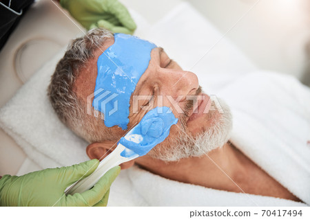 Contented elderly man having a facial mask for his skin 70417494