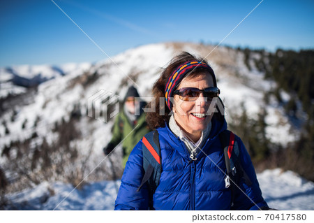 Senior woman with husband hiking in snow-covered winter nature. 70417580