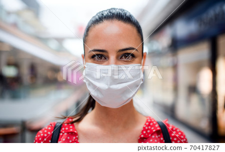 Woman with face mask standing indoors in shopping center, coronavirus concept. Woman with face mask standing indoors in shopping center, coronavirus concept. 70417827