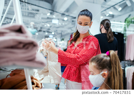 Woman with face mask shopping in clothes shop, coronavirus concept. Woman with face mask shopping in clothes shop, coronavirus concept. 70417831