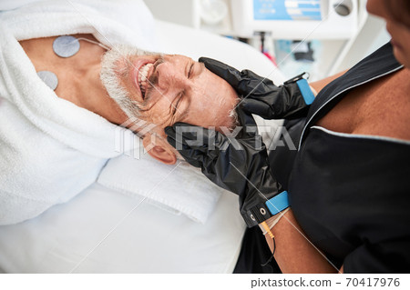 Happy senior citizen receiving facial treatment at spa 70417976