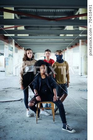 Group of teenagers gang standing indoors in abandoned building, looking at camera. 70418491