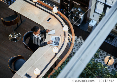 Attentive brunette female staring at screen of laptop Attentive brunette female staring at screen of laptop 70418752