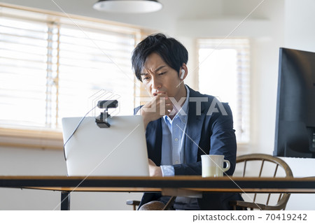 Telework image of a man frowning while looking at a computer screen 70419242