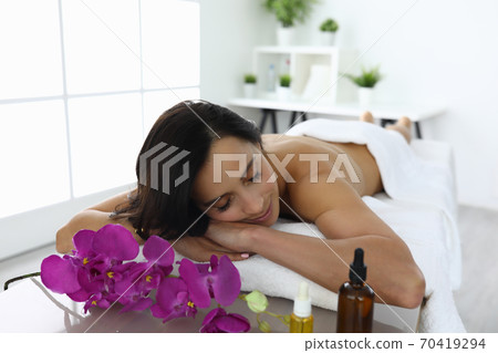 Young woman with closed eyes lies on couch in beauty salon Young woman with closed eyes lies on couch in beauty salon 70419294