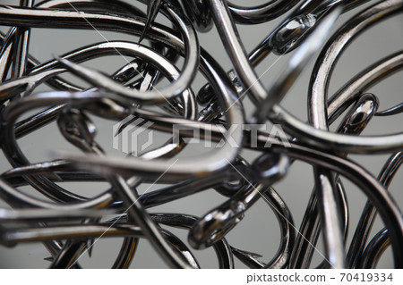 Lot of metal fishing hooks lie on table closeup 70419334