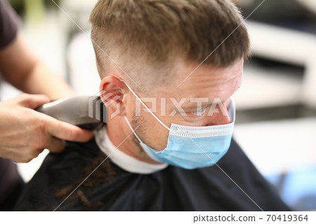 Young man in protective mask on face makes haircut in beauty salon portrait Young man in protective mask on face makes haircut in beauty salon portrait 70419364