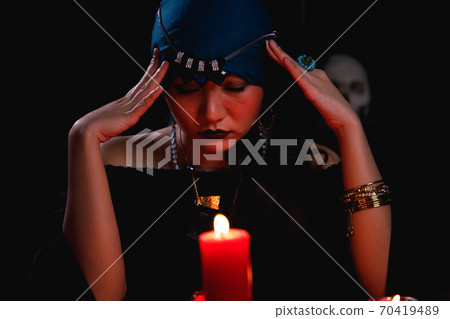 Fortune teller casting spell over red candle during forecasting future. 70419489