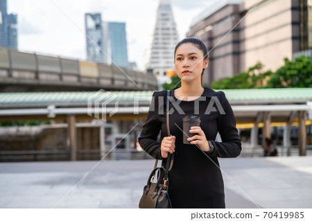 woman holding a cup of coffee and thinking about problem of her business in city 70419985