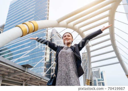 successful business woman with arms raised in city successful business woman with arms raised in city 70419987