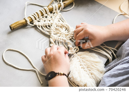 Female hands weave macrame the home workshop. Boho lifestyle. Hobby hobby concept. Selective focus horizontal frame. 70420246