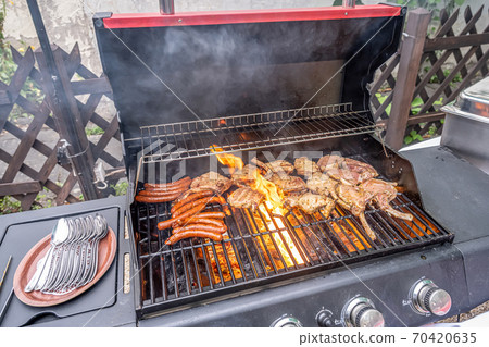 Tomahawk rib beef steak ans sausages on hot black grill with flames bbq Tomahawk rib beef steak ans sausages on hot black grill with flames bbq 70420635