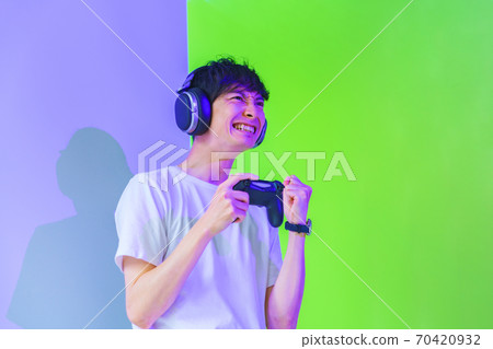 [電子競技圖片]一位男性玩家，在紫色和綠色的燈光下對控制器感到興奮 70420932