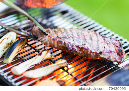 Grilling beef steaks over a barbecue over a barbecue [The real pleasure of the outdoors] 70420993