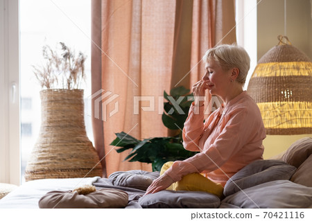 Senior woman practicing yoga at home, making Alternate Nostril Breathing exercise, nadi shodhana pranayama Senior woman practicing yoga at home, making Alternate Nostril Breathing exercise, nadi shodhana pranayama 70421116